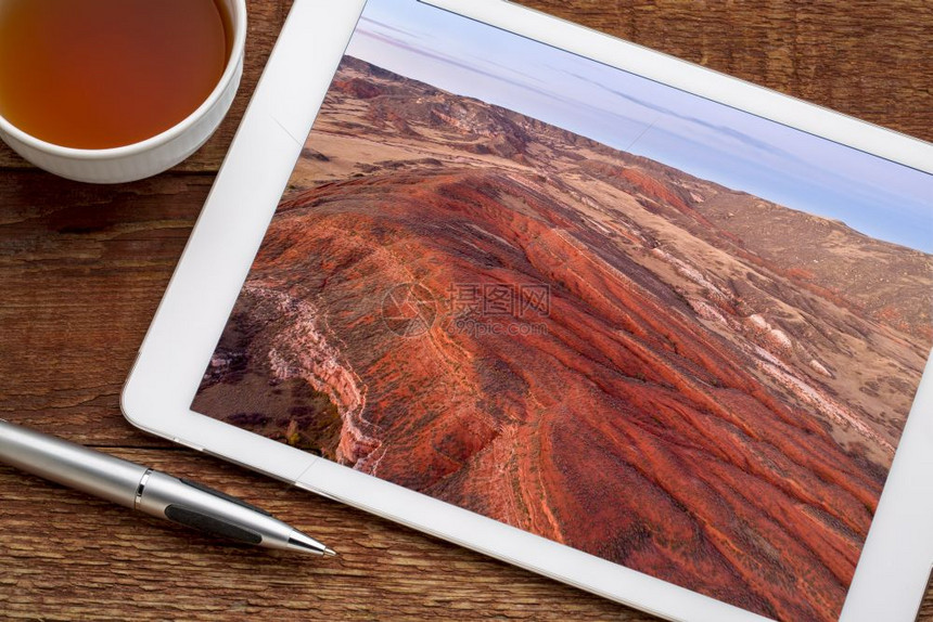 在科罗拉多北部洛基山丘陵的上空用红色沙石和峡谷在数字平板上审查空中图像图片