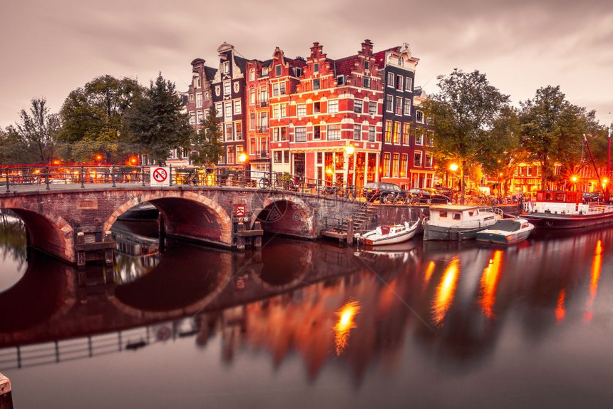 阿姆斯特丹运河和桥梁的夜间城市景色阿姆斯特丹运河桥梁和典型的房屋船只和自行车晚上清晨蓝色时荷兰图片