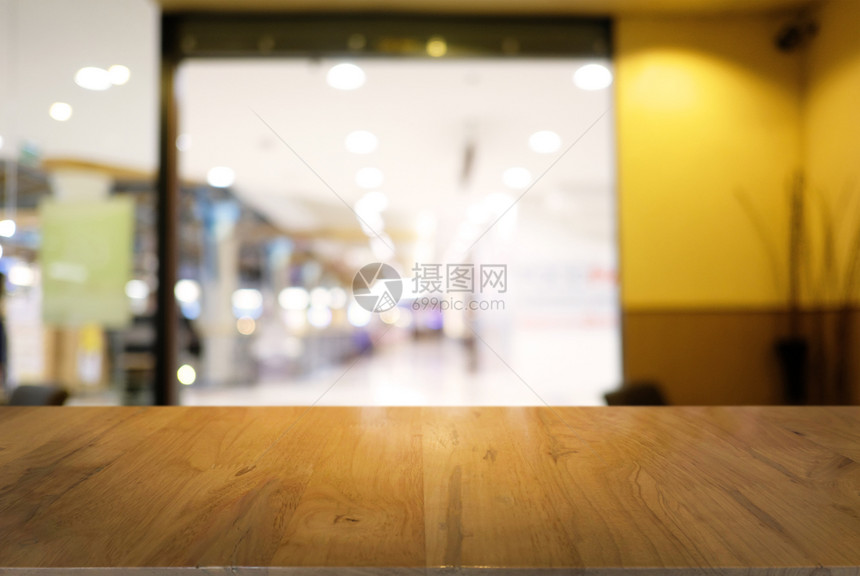 咖啡店的抽象模糊背景面前的空黑木桌可以用于显示或装配产品图片