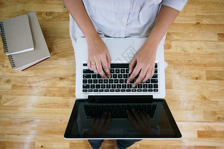 临时商业女在网上用笔记本电脑工作笔记本电脑在她家里的键盘上手动用笔记本电脑隔离屏幕背景图片