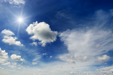 明亮的太阳和白云笼罩在一片史诗般的黑暗蓝天幕后图片