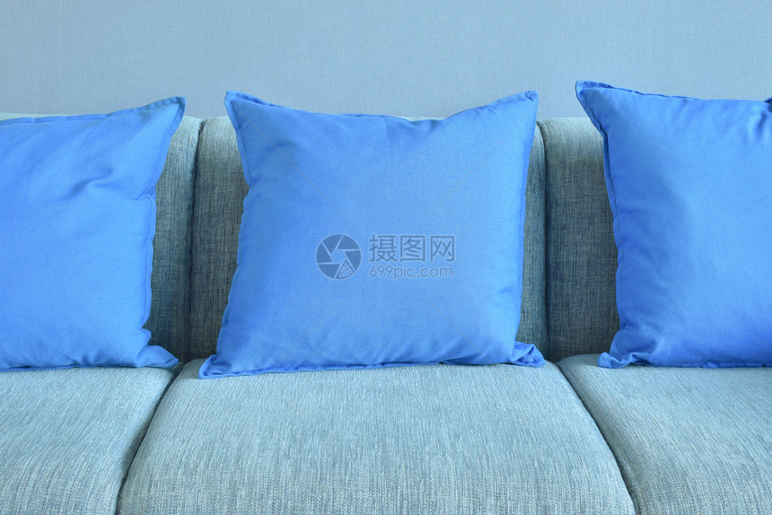 蓝墙背景的浅色沙发上枕头图片