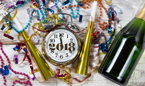 显示2018年新午夜的时钟周围环绕着派对物体和香槟图片