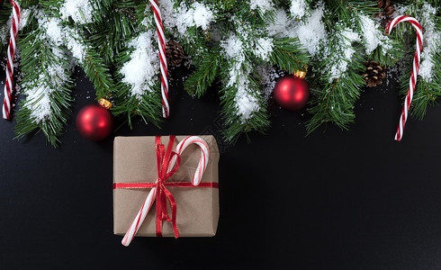 糖针装饰圣诞礼物有雪绿色的树枝糖果甘蔗和黑色背景的红装饰品背景