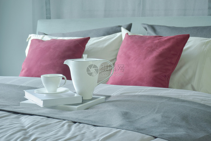 装有红色天鹅绒枕头的陶瓷茶和书架铺在床上图片