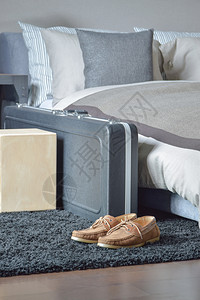 现代式卧室床边黑地毯上的棕色皮鞋和行李图片
