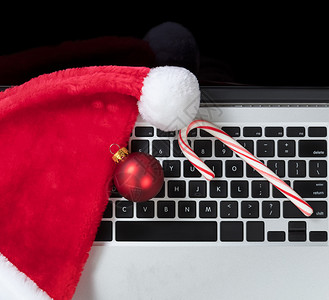 圣诞老人帽子和糖果甘蔗放在顶电脑键盘上在圣诞节购物季图片