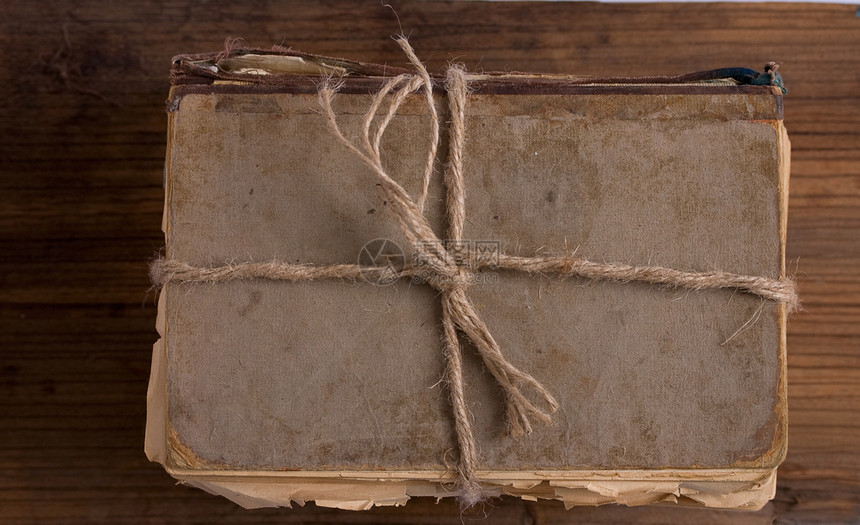一本破旧的书被绑在粗木背景的绳子上图片