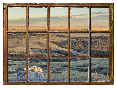 在科罗拉多山丘的日落时草原上从古老的被冷漠用脏玻璃砸碎的窗户中可以看到背景图片