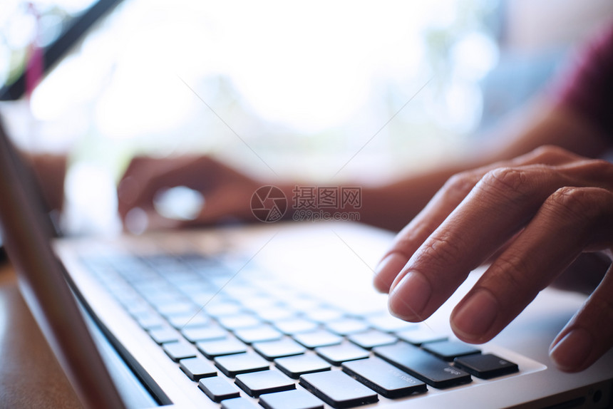 男人用笔记本电脑在木制桌上工作手打字在键盘上图片