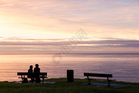 情侣在海边的长椅上看晚霞高清图片