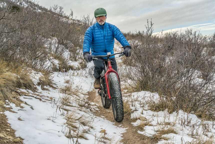 一名高级男骑着肥自行车在CheyenneRim的CheyenneRim红山开放空间秋末或冬季风景和一些雪图片