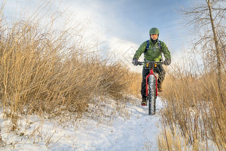 年轻的男人在雪地里骑山地车图片