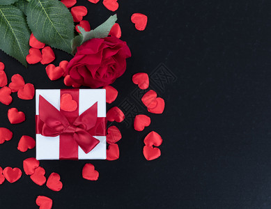 一个礼物盒心脏形状和一朵红玫瑰的顶部视线放在黑暗石头背景上图片