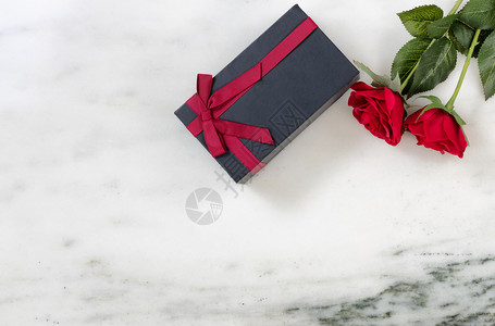 Marble石碑背景的红玫瑰和深礼物盒图片