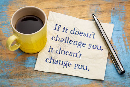 如果它doest挑战你它会改变用咖啡在餐巾纸上写字背景图片