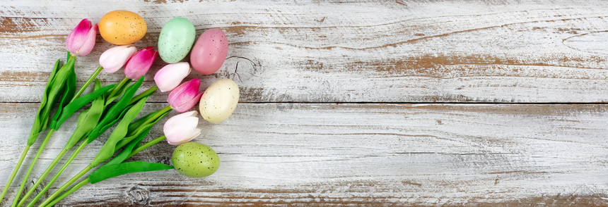 彩色的郁金香和满鸡蛋的篮子在复活节背景的生锈白木上下边框形成鸡蛋图片