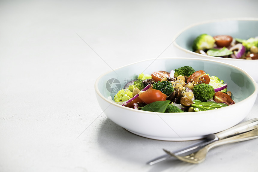 健康素食能刺激沙拉配有鸡豆花椰菜西红柿洋葱菠菜和蓝盘坚果放在混凝土背景选择焦点上图片