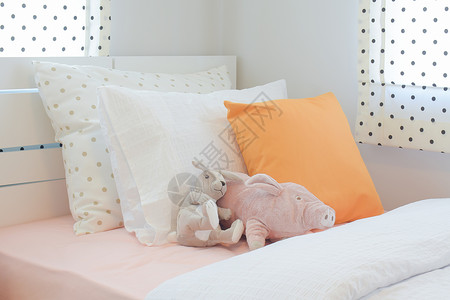 在可爱风格的卧室橙色枕头旁边床上布置小猪和兔子娃图片