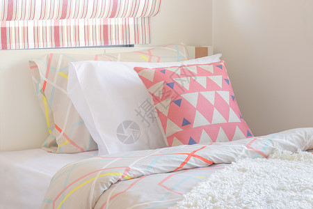 粉红三角型枕头放在甜色风格卧室角的床上图片