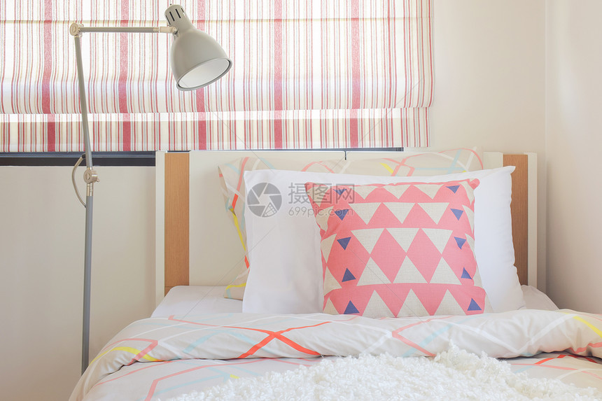 珊瑚粉红三角形圆枕头放在床上旁有折叠阅读灯图片