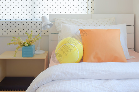 甜彩计划卧室床上的黄花球和橙色枕头图片