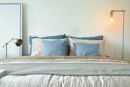 现代式床铺上的工业风格读灯和蓝枕头图片