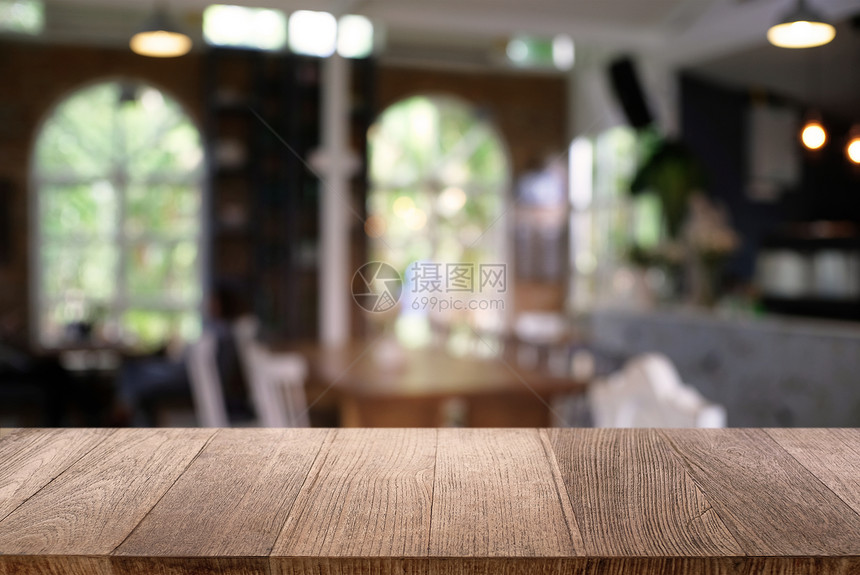 咖啡店的抽象模糊背景面前的空木板可以用来显示产品模版图片