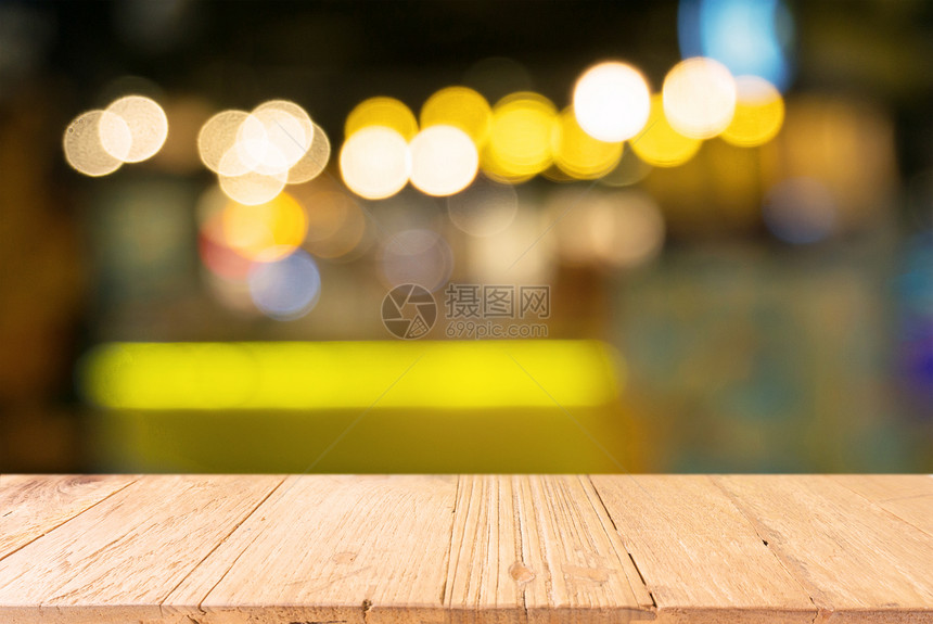 Bokeh光线的抽象模糊背景面前的空木制桌可用于显示或蒙合产品图片