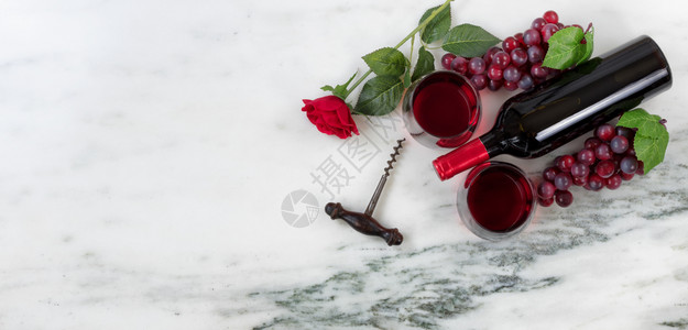 红色葡萄酒瓶杯软木瓶和天然大理石上的玫瑰图片