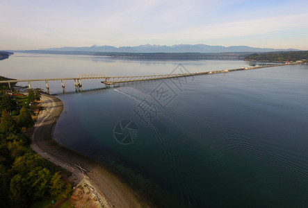 一艘船沿向南行驶在背景中沿奥林匹克山脉附近运河海湾桥下行驶图片