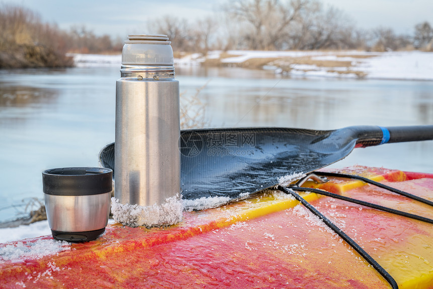 科罗拉多州冬季皮艇圣瓦林溪岸的红白水皮艇冰面甲板上有热茶的水瓶图片