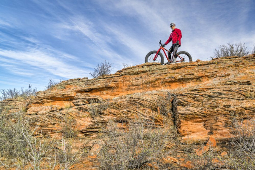 在科罗拉多山丘的沙石悬崖上骑着肥自行车的男骑手秋天风景图片