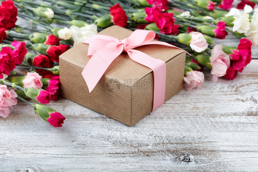 白色风化木板背景上彩色康乃馨的礼品盒图片