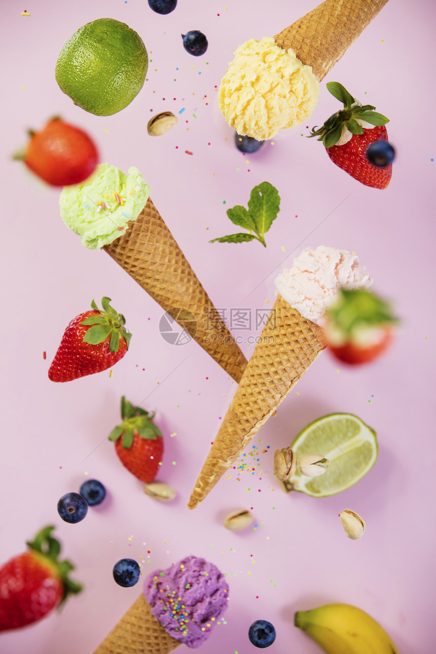 甜多彩的冰淇淋在华夫饼锥中喷洒和配料在粉红色破碎的陈年背景上落下或飞动图片