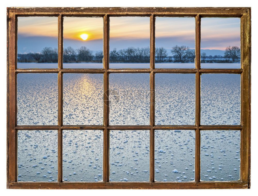 在科罗拉多州的冰冻湖上日落的透过古老的玻璃窗图片