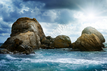 海景中的岩石天空乌云和明亮太阳图片