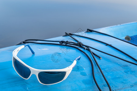 运动太阳镜放在一个湿的甲板上起立在桨图片