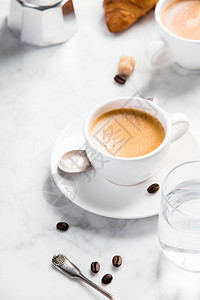 白大理石背景的咖啡成分含水和羊角面包的白色杯子中咖啡浓缩图片