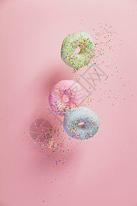甜圈喷洒在粉红色面背景上落或飞起来图片