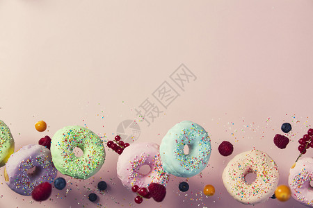 甜圈喷洒和浆果在粉色糊面背景下落或飞起来背景图片