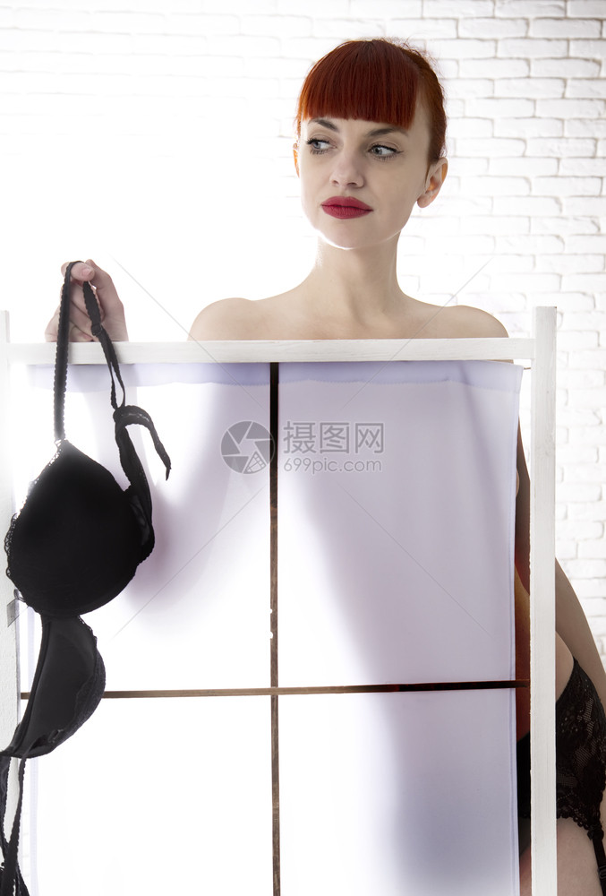 美丽的年轻女孩在折叠屏幕后穿衣服图片