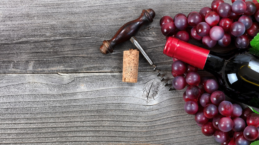 红酒和葡萄的瓶子未开红酒和葡萄瓶装在旧木材上图片