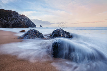 葡萄牙日出时在Adraga岩石海滩起潮在Adraga岩石海滩起潮图片