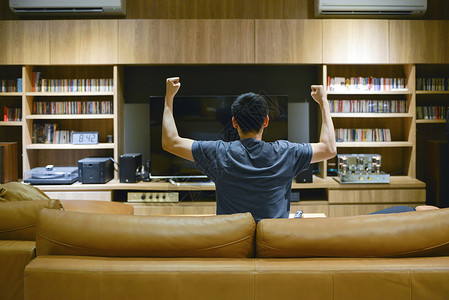 亚洲男人晚上在客厅电视前欢呼图片