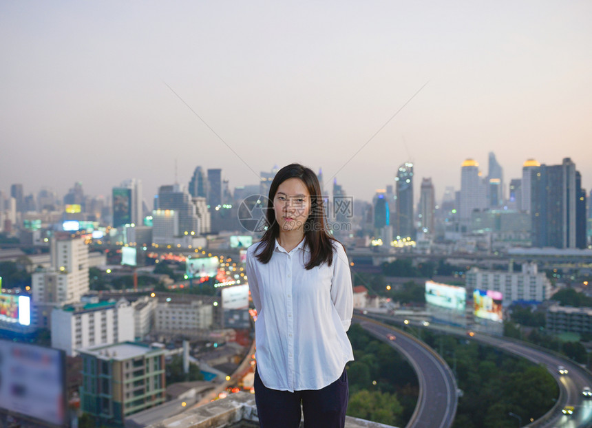 亚洲商业妇女看着曼谷市在屋顶的日落亚洲商业妇女看着曼谷市在屋顶的日落图片