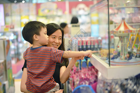 年轻亚洲母亲和孩子在购物中心玩具图片
