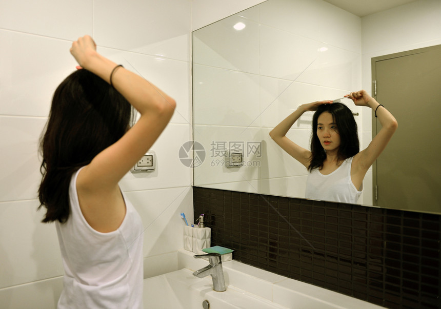 亚洲女人在浴室的镜子前梳头发图片