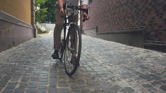 时尚青年男子在铺路的旧自行车上骑着老式自行车图片