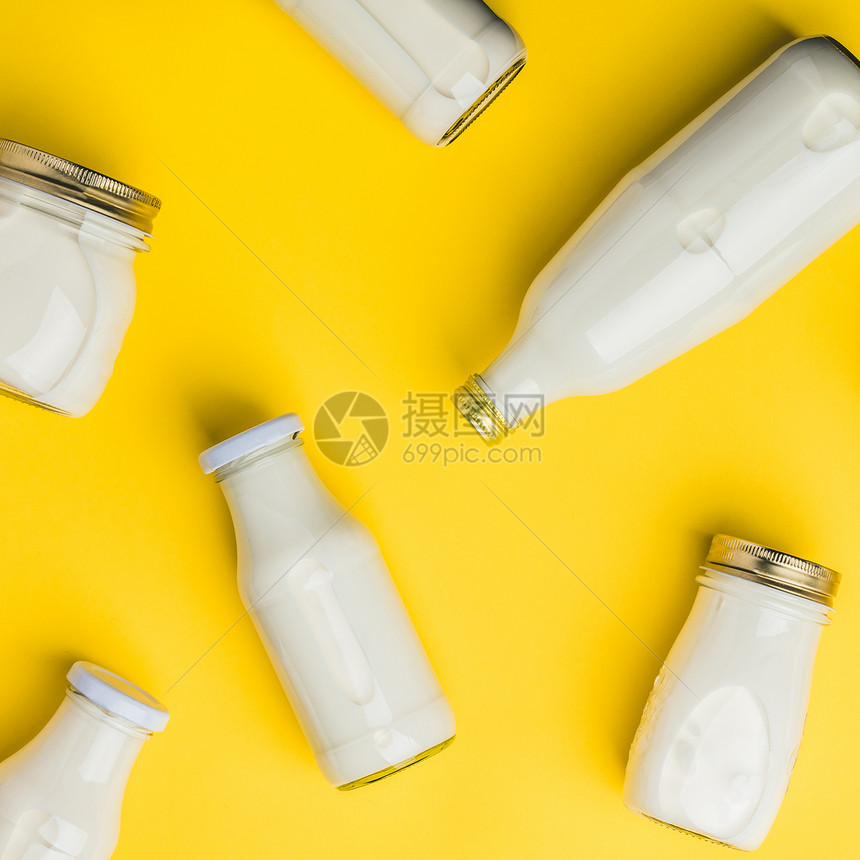 各种奶瓶黄色背景平铺图片